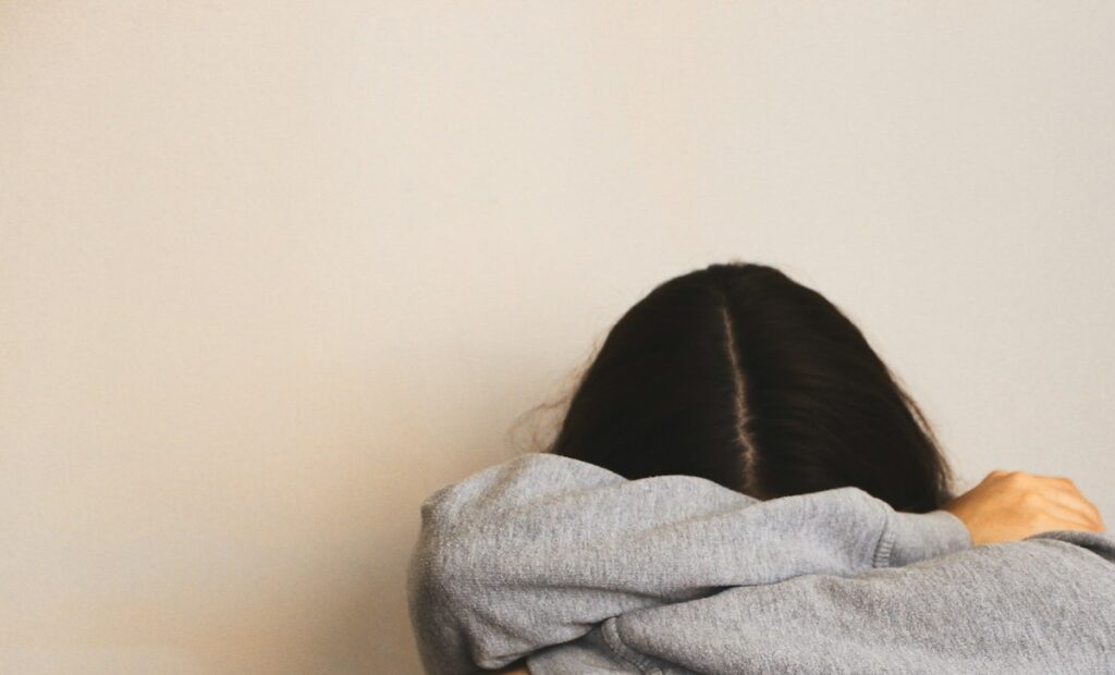 a woman sitting on the floor with her arms wrapped around her head